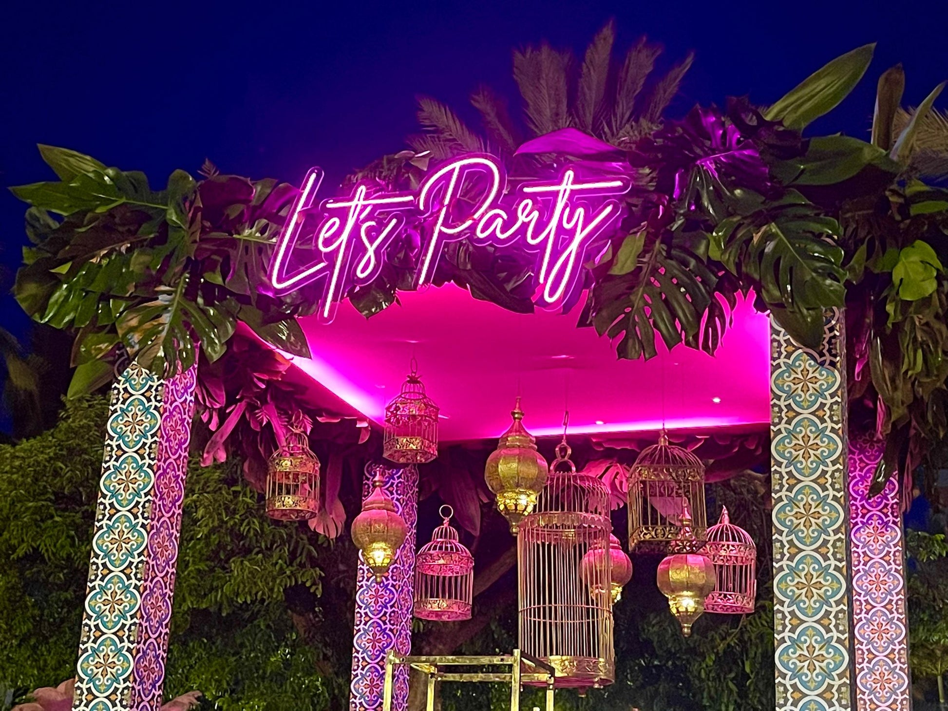 a lit up party entrance with lanterns and birdcages