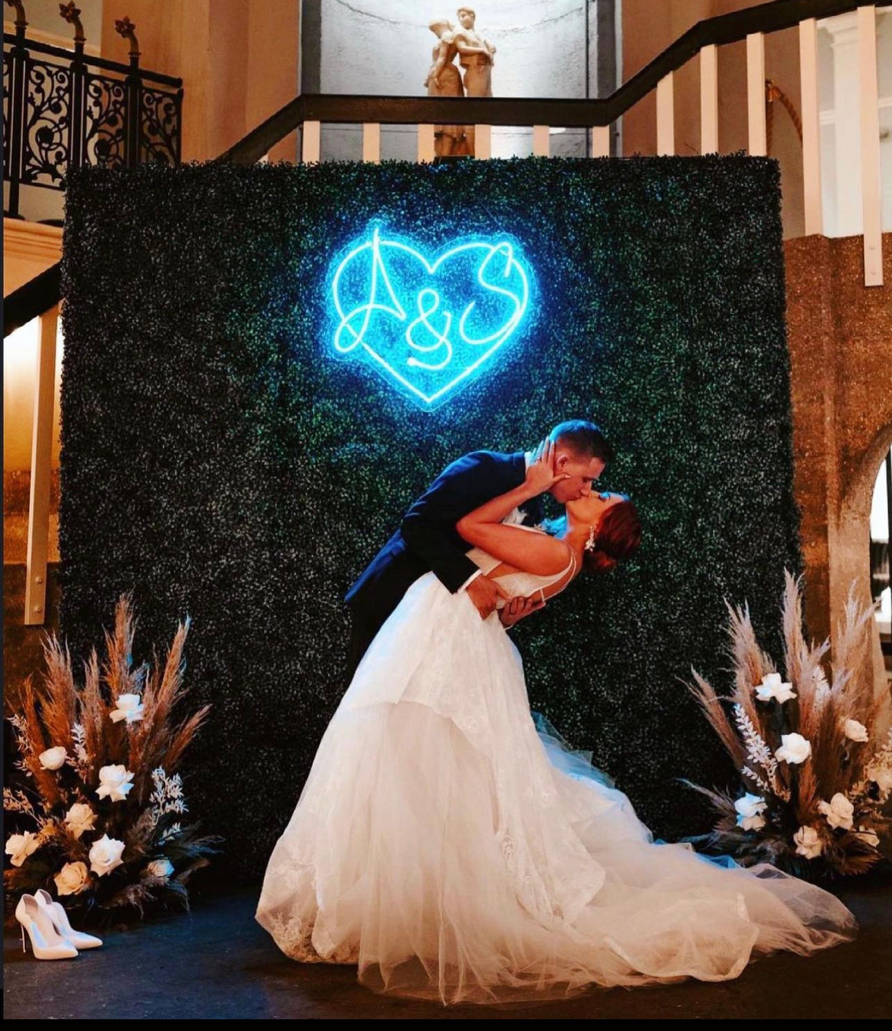 a bride and groom kissing in front of a neon sign