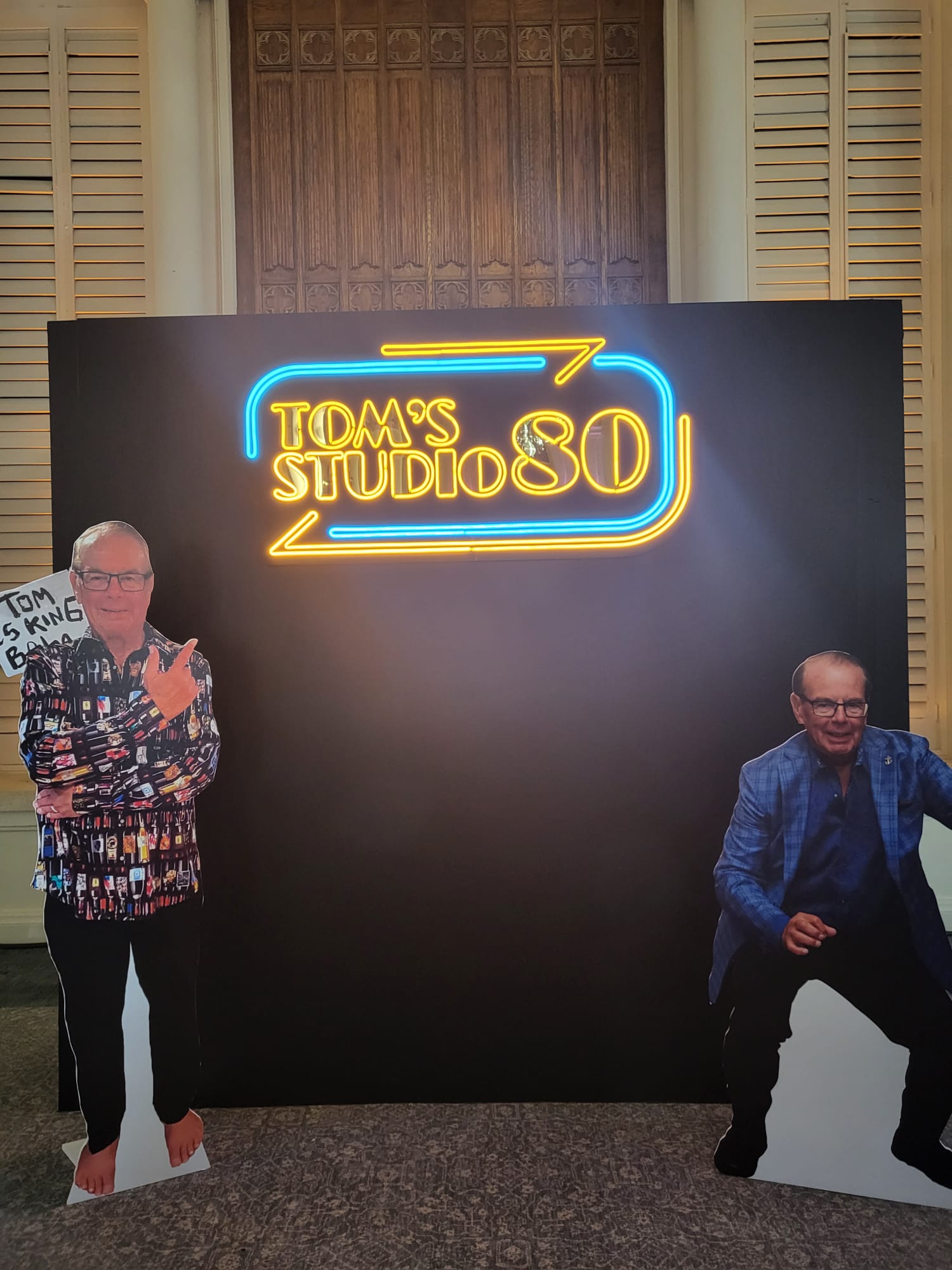 two people standing in front of a sign that says tom's studio