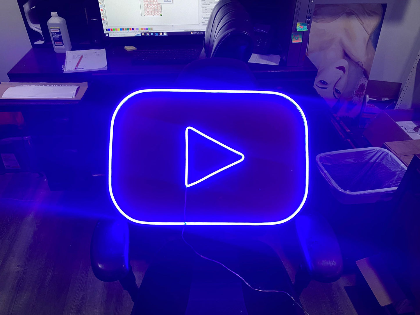 a computer desk with a monitor and a blue play button